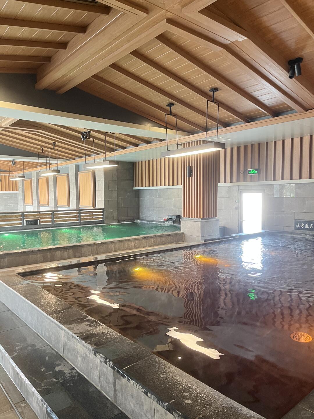 Spacious indoor pool area at He Ri Jun Bathhouse featuring warm wooden beams and a calm, modern layout.