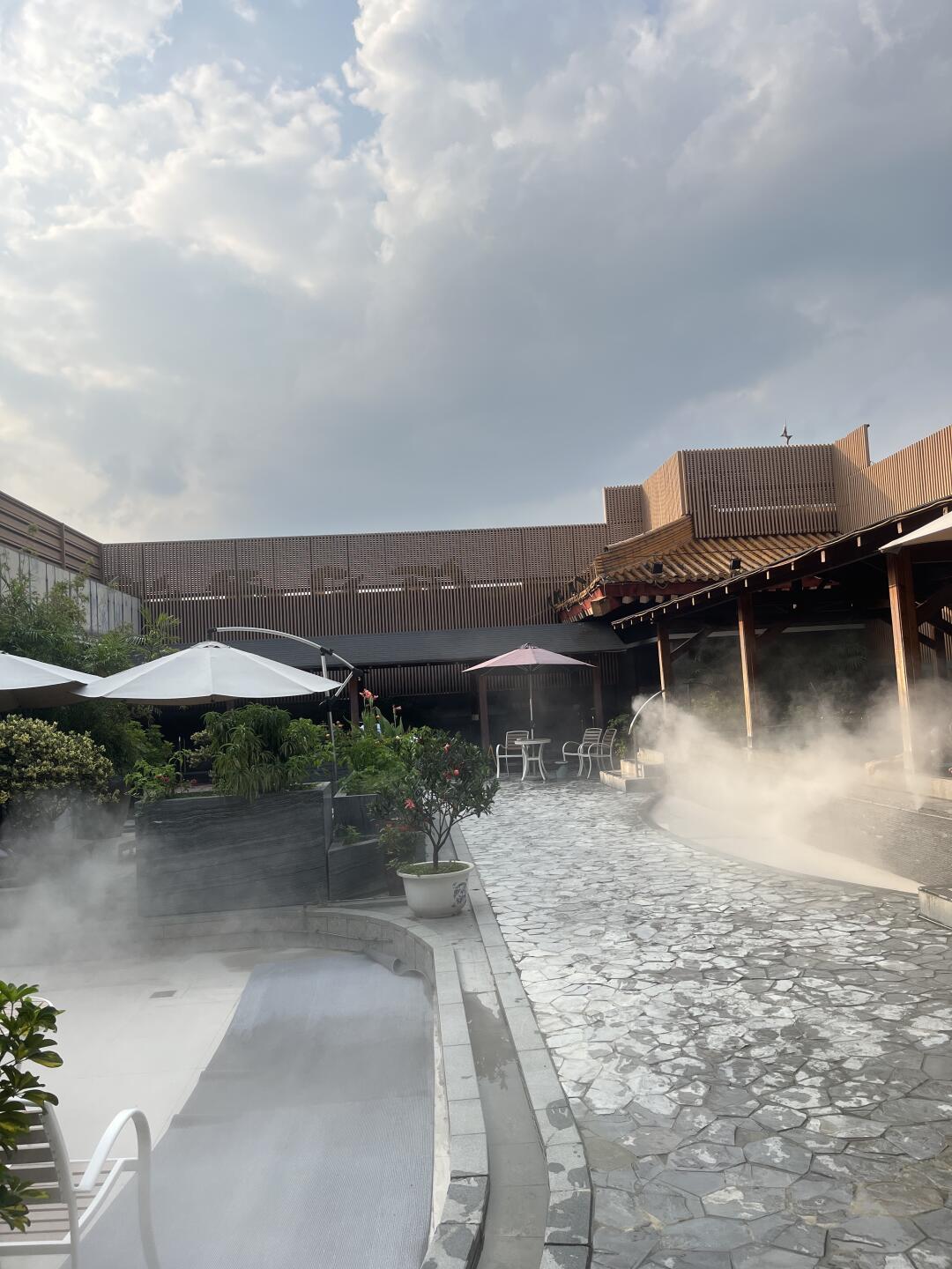 Outdoor hot spring area at He Ri Jun Bathhouse featuring steaming pools and a peaceful open-air setting.