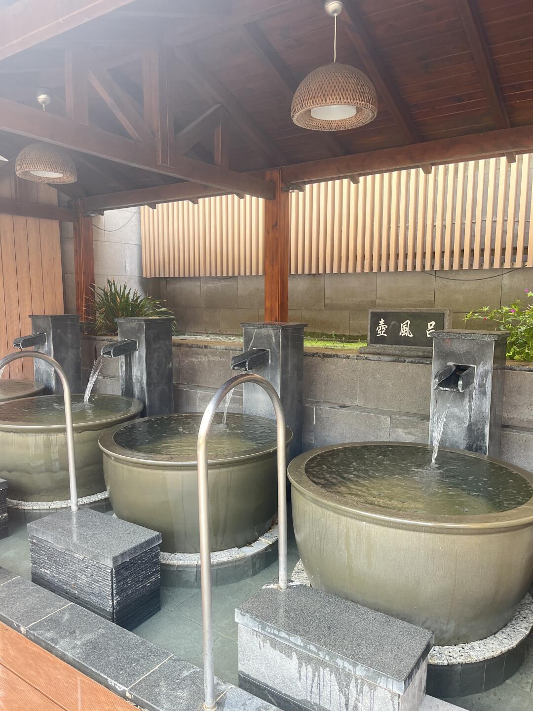 Indoor soaking area at He Ri Jun Bathhouse with individual round tubs and minimalist wooden design.